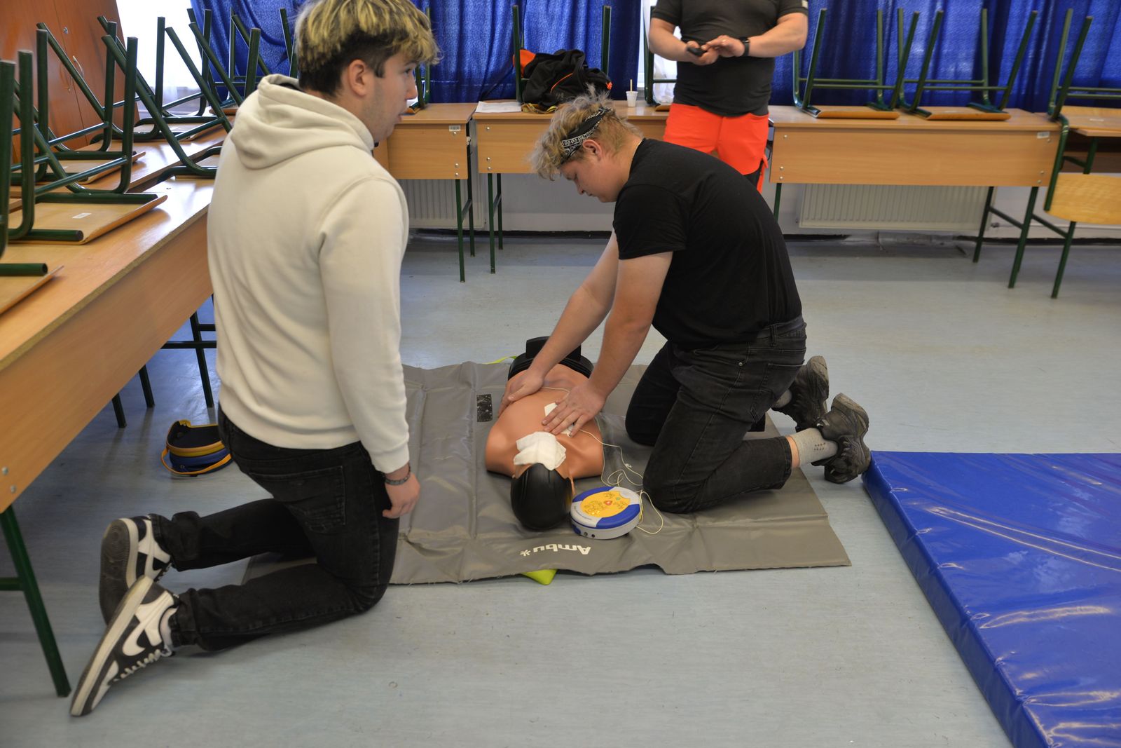 Students practicing CPR on a training manikin in a classroom